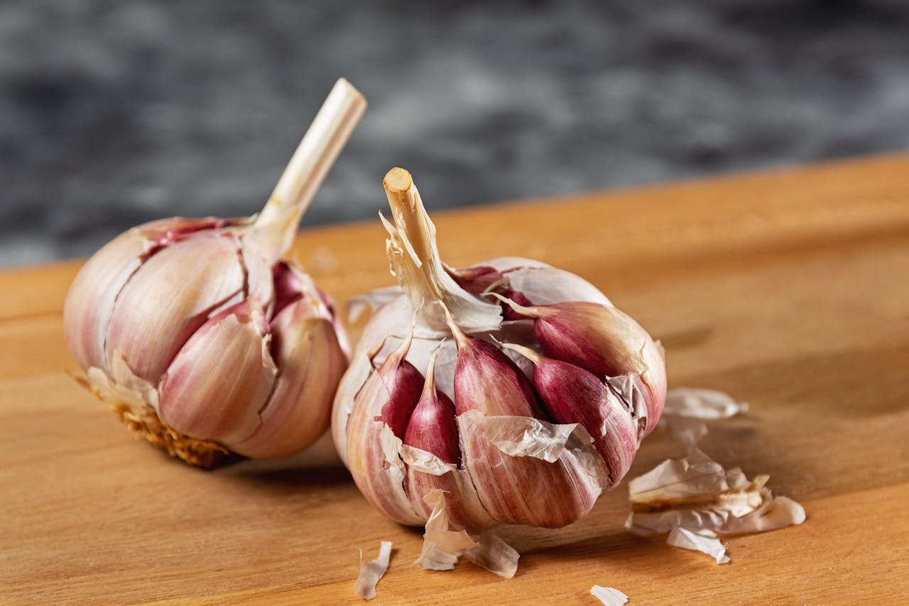 Close-up of fresh garlic bulbs resting on a wooden cutting board. Ideal cooking ingredient.